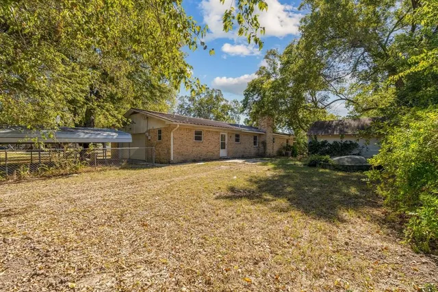 a backyard of a house with large trees and outdoor seating