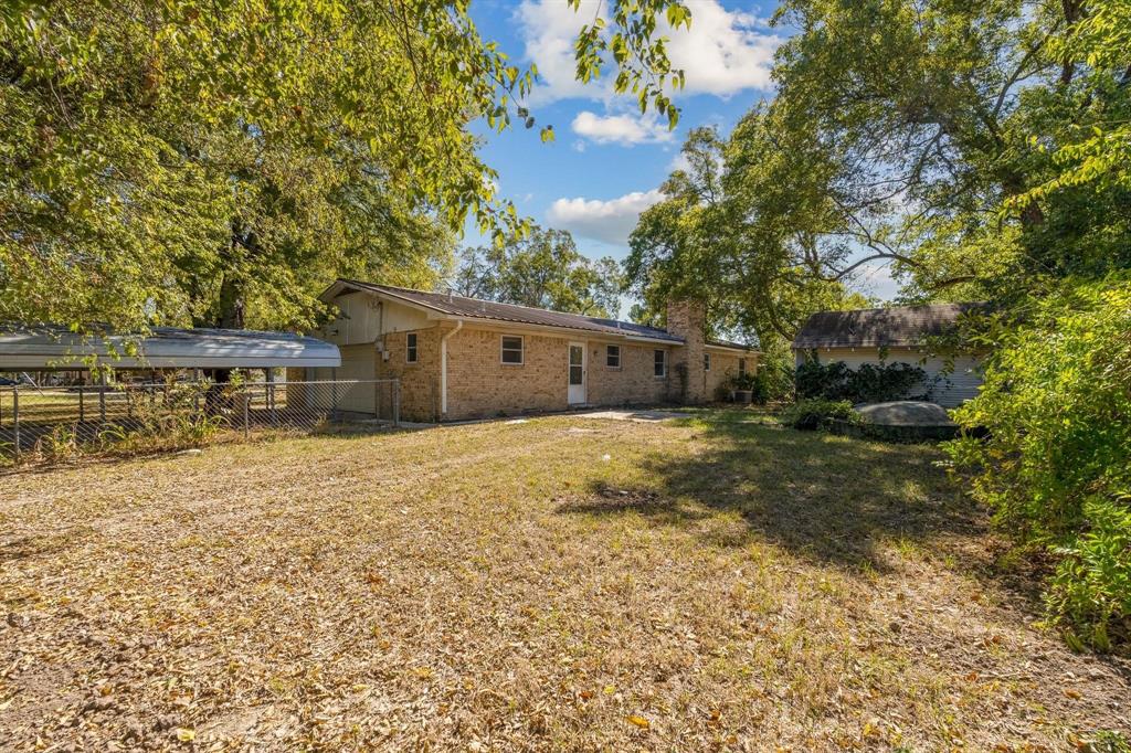 921 Evans Street Bonham, TX 75418 - Photo 24 of 28 a backyard of a house with large trees and outdoor seating