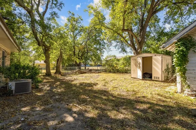 a backyard of a house with large trees and a barn