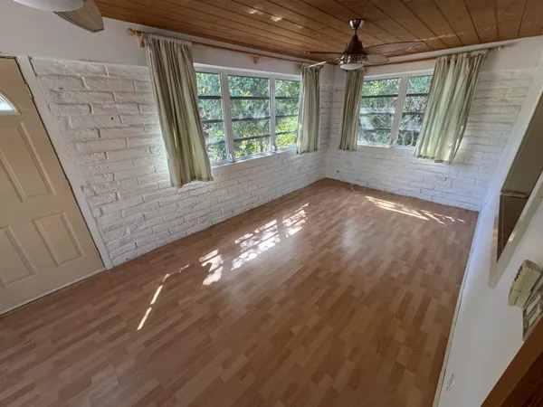 a view of empty room with wooden floor and fan