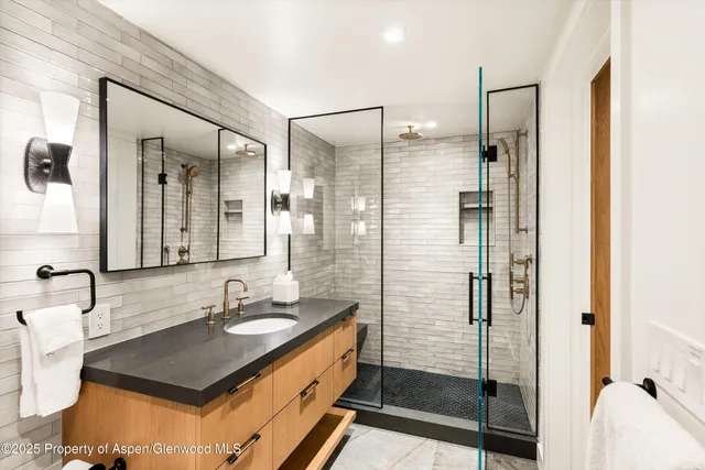 a bathroom with a granite countertop sink a mirror and shower