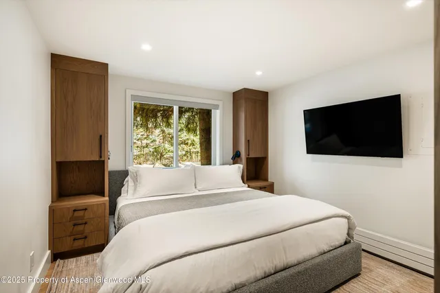 a bedroom with a large bed and a flat tv screen on dresser