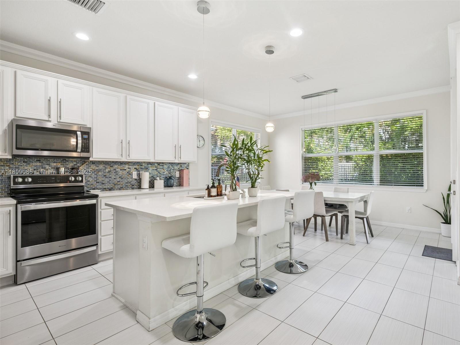 4325 Large Leaf Lane Hollywood, FL 33021 - Photo 17 of 72 a kitchen with stainless steel appliances kitchen island granite countertop a stove a sink a dining table and chairs