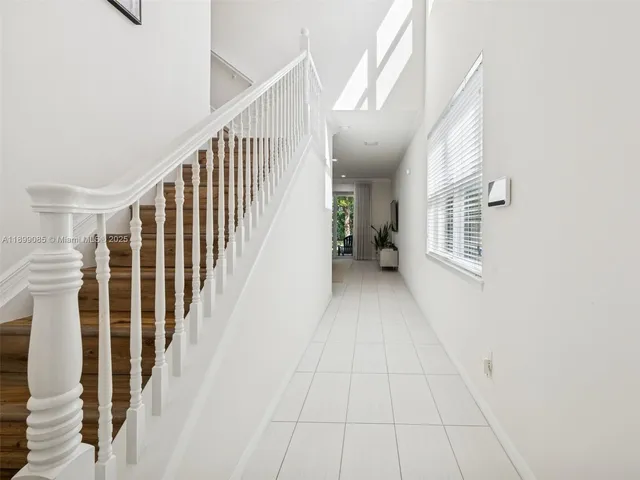 a large white kitchen with a large window a sink and stainless steel appliances