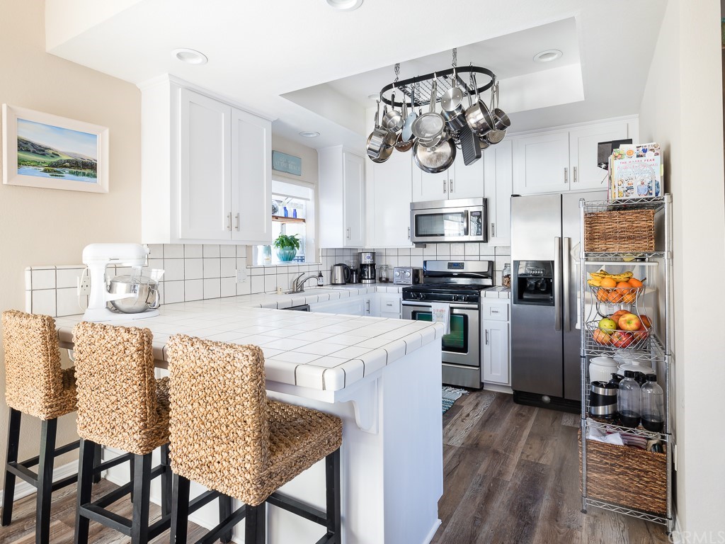 408 Richmond Street, Unit 10 El Segundo, CA 90245 - Photo 8 of 24 a kitchen with stainless steel appliances granite countertop a stove top oven a sink a dining table and chairs with wooden floor