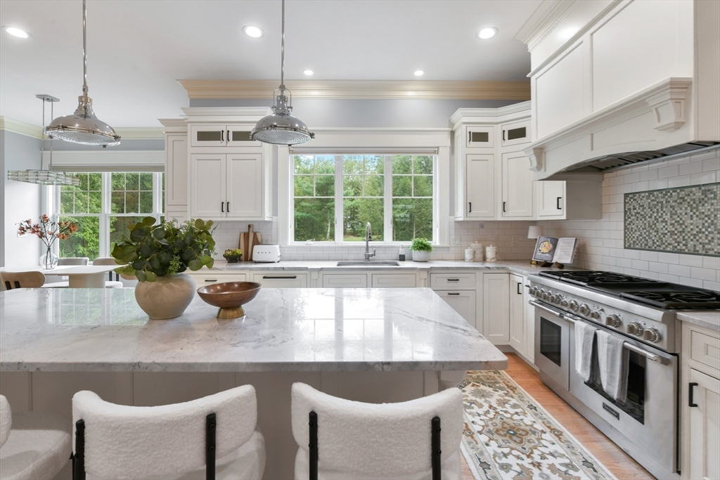 6 Norwich Road Wellesley, MA 02481 - Photo 7 of 34 a kitchen with stainless steel appliances granite countertop a stove a sink dishwasher a dining table and chairs with wooden floor
