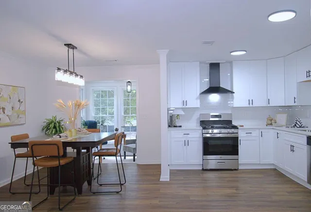 a open kitchen with granite countertop a stove a sink a dining table and chairs with wooden floor