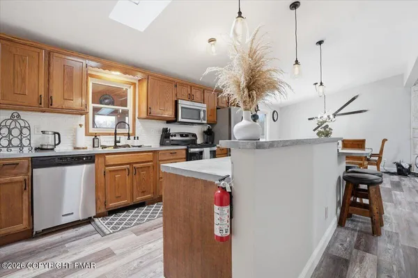 a kitchen with stainless steel appliances granite countertop a refrigerator a stove a sink dishwasher and a microwave with wooden floor