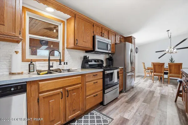 a kitchen with stainless steel appliances granite countertop a stove a sink dishwasher and a refrigerator with wooden floor