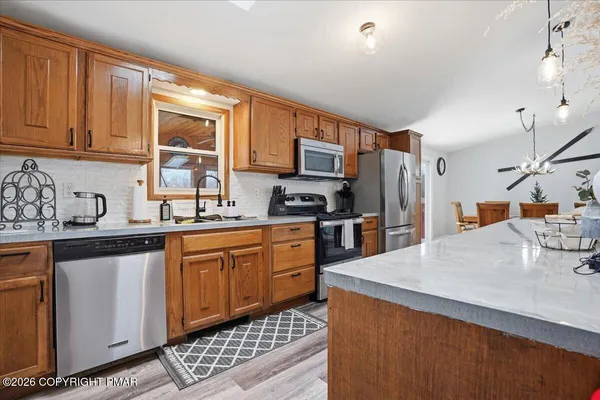 a kitchen with stainless steel appliances a sink a stove a refrigerator cabinets and a window