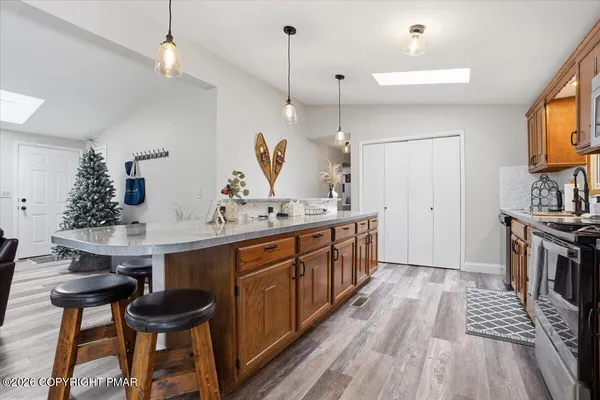 a spacious kitchen with stainless steel appliances granite countertop a sink a stove and a wooden floor