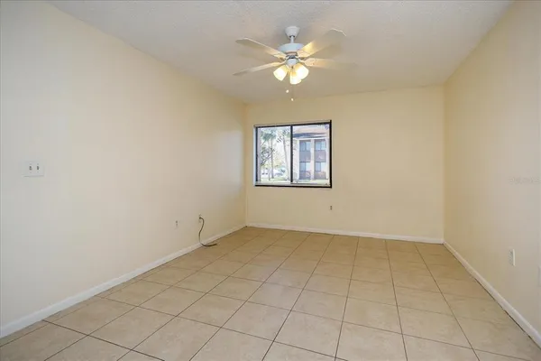 an empty room with windows and chandelier fan