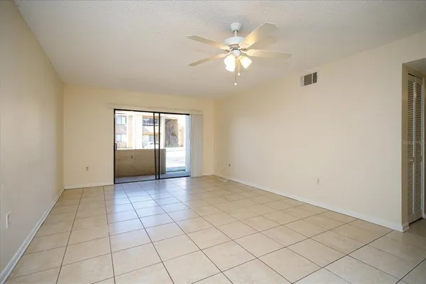 a view of an empty room with window and chandelier fan