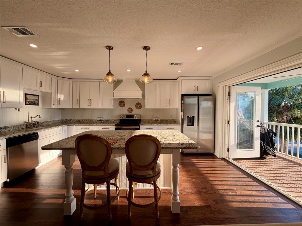6525 Engram Road New Smyrna Beach, FL 32169 - Photo 21 of 36 a kitchen with granite countertop wooden floor cabinets and stainless steel appliances