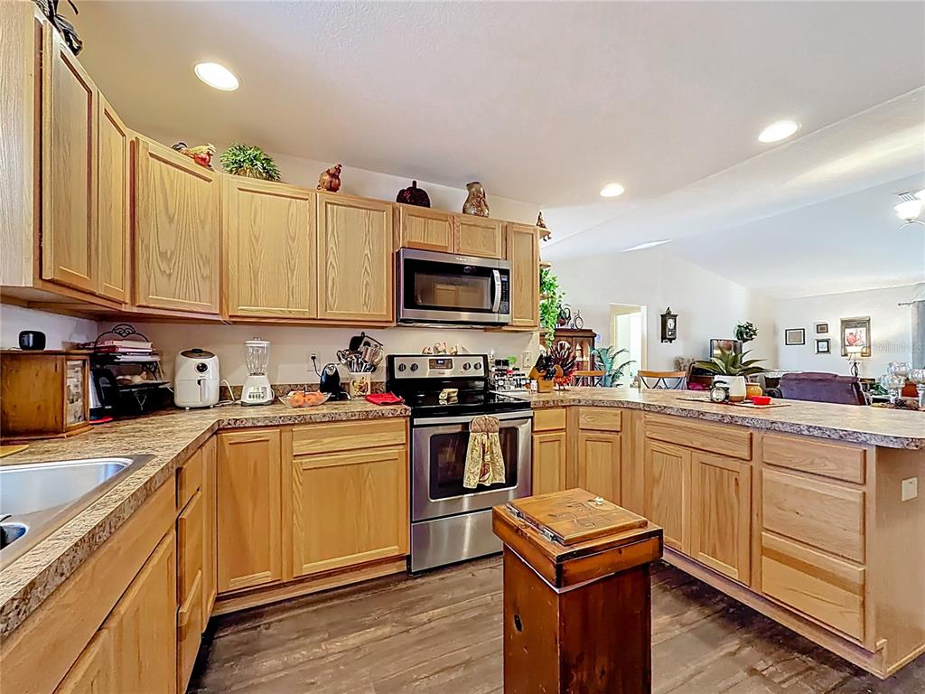 3531 Thorne Path Oxford, FL 34484 - Photo 16 of 56 a kitchen with stainless steel appliances granite countertop a stove top oven a sink dishwasher and white cabinets with wooden floor
