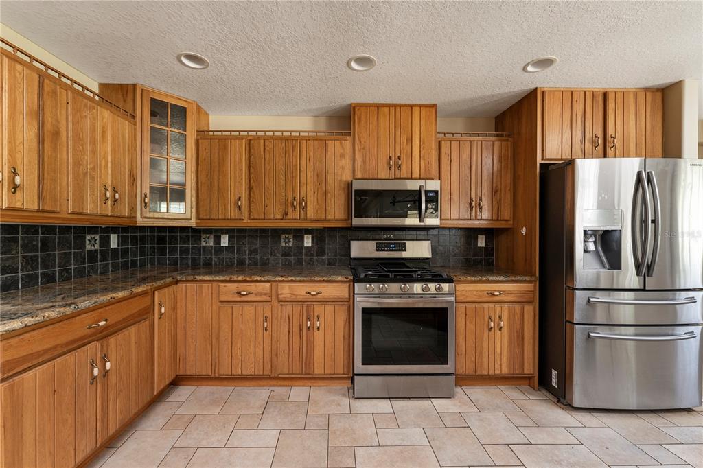 16017 Johns Lake Road Clermont, FL 34711 - Photo 15 of 62 a kitchen with stainless steel appliances granite countertop a refrigerator and a stove top oven