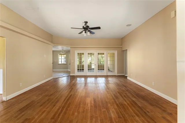 a view of empty room with wooden floor and fan