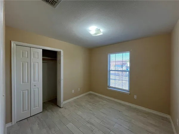 a view of an empty room with wooden floor and closet