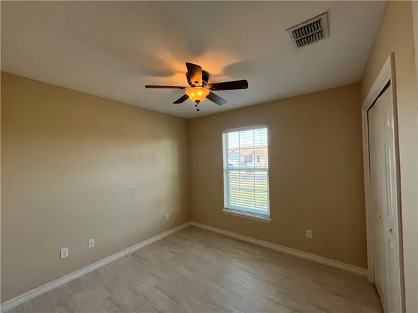 a view of empty room with wooden floor and fan
