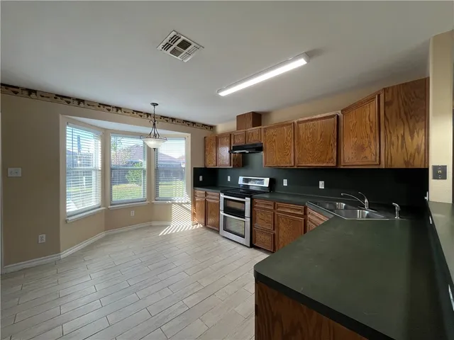 a large kitchen with granite countertop a stove top oven a sink and dishwasher
