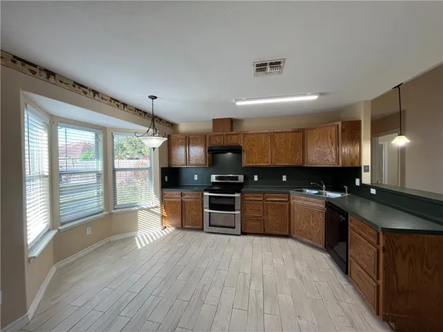 a large kitchen with granite countertop a large counter top stainless steel appliances and a large window