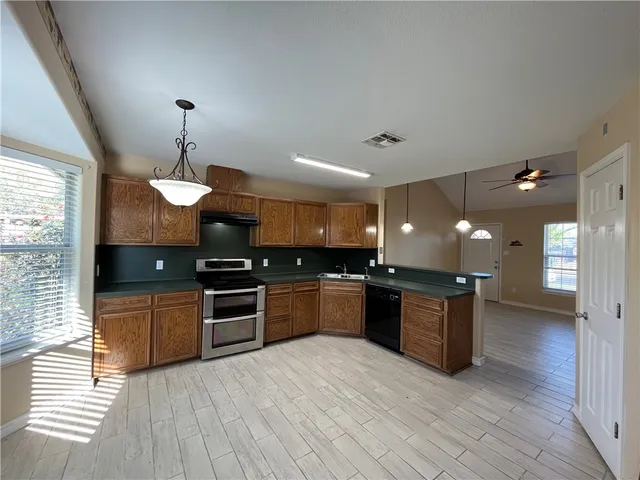 a large kitchen with stainless steel appliances granite countertop a stove and a wooden floors