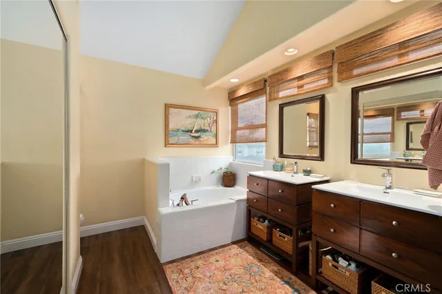 a bathroom with a double vanity sink mirror and bathtub