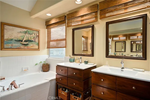 a bathroom with a double vanity sink mirror and bathtub