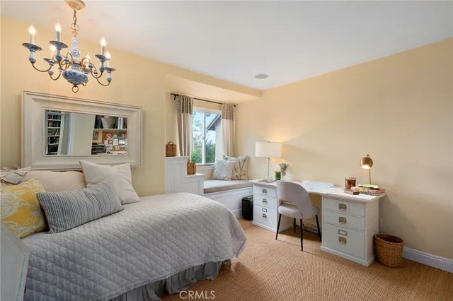 a spacious bedroom with a bed a chandelier and a dresser