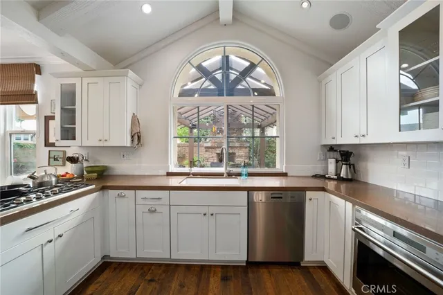 a kitchen with white cabinets white stainless steel appliances and a window