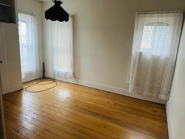 an empty room with wooden floor and window