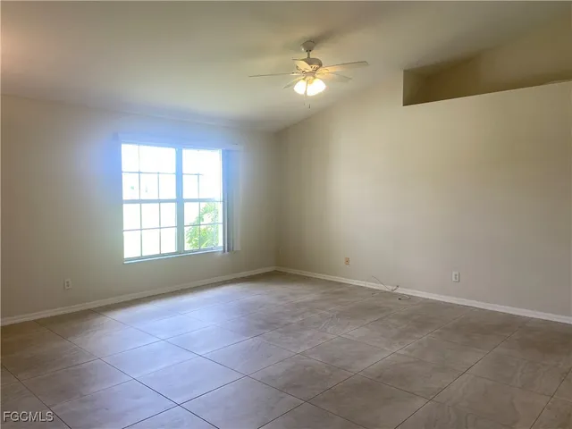 an empty room with windows and chandelier fan
