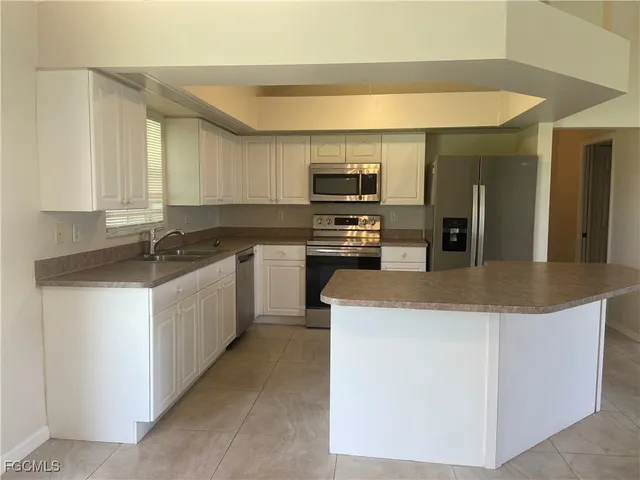 a kitchen with kitchen island granite countertop a sink a counter top space appliances and cabinets