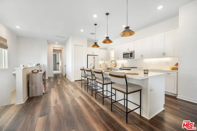 a large white kitchen with lots of counter space a sink appliances and cabinets