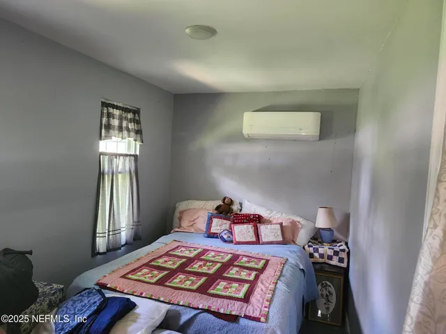 a bedroom with a bed and a dresser with wooden floor