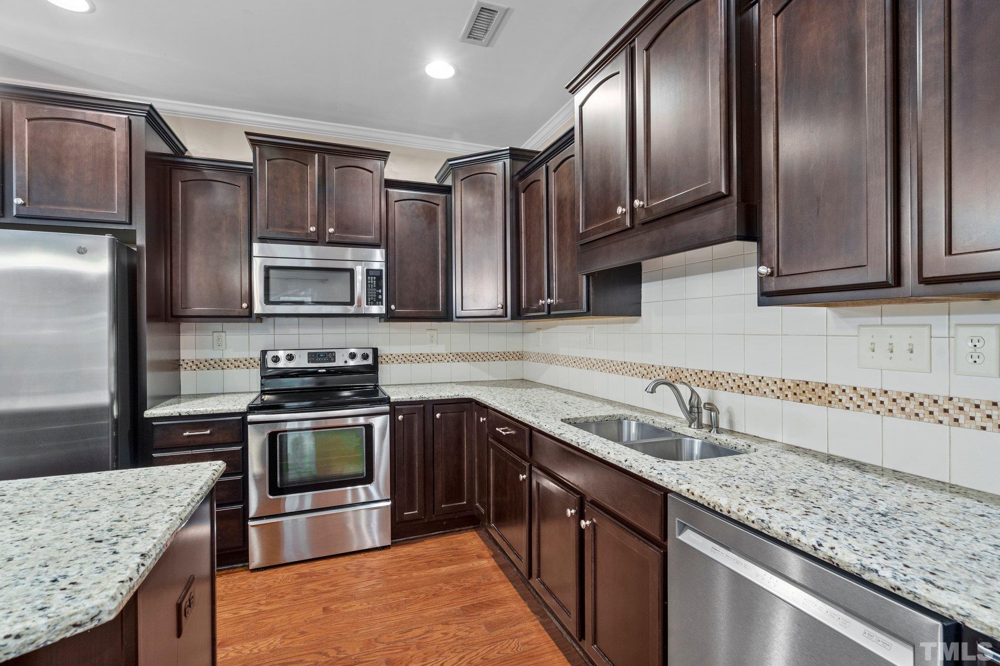 2421 Memory Ridge Drive Raleigh, NC 27606 - Photo 5 of 31 a kitchen with stainless steel appliances granite countertop a sink stove microwave and refrigerator