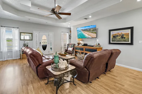 a living room with furniture a wooden floor and a ceiling fan