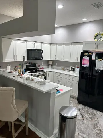 a kitchen with a sink a stove a refrigerator and chairs