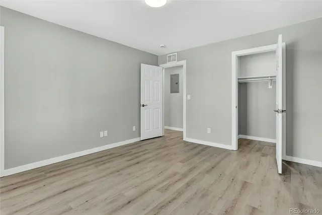 an empty room with wooden floor & closet area