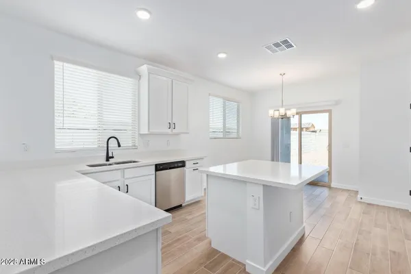 a large white kitchen with sink and dishwasher a stove top oven with wooden floor