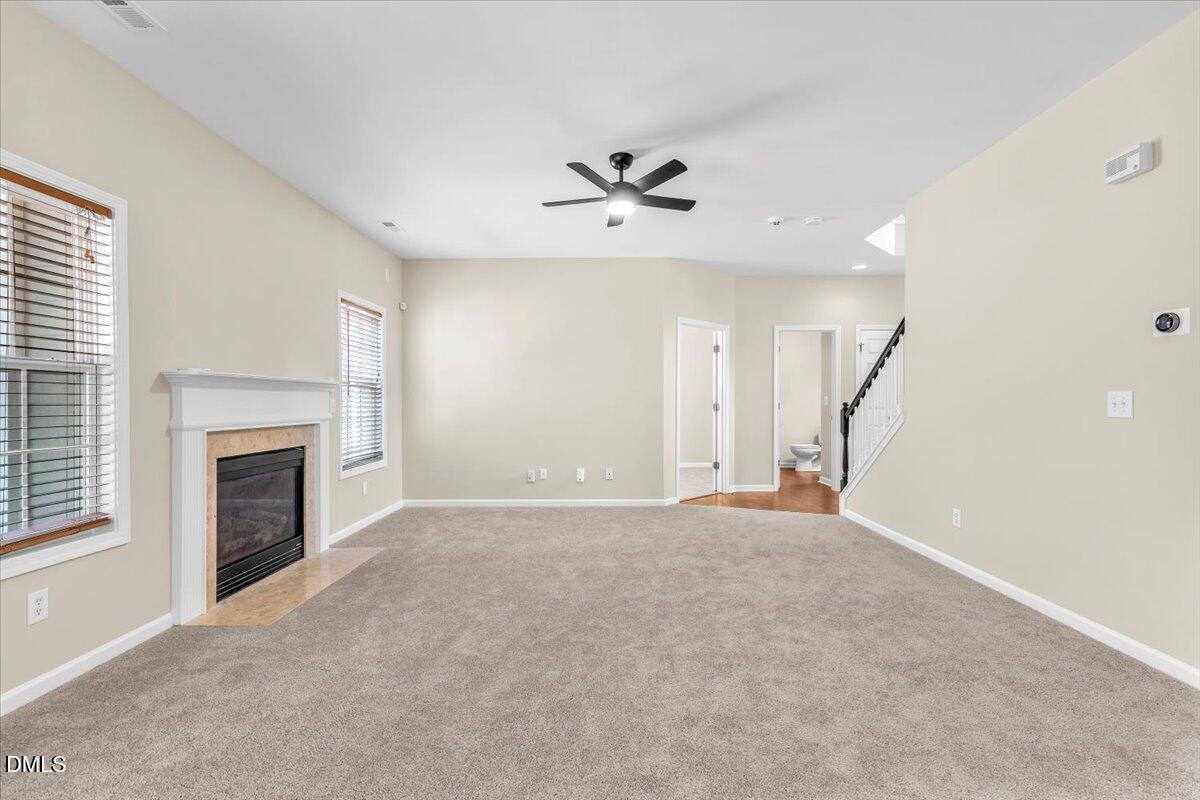 708 Straywhite Avenue Apex, NC 27539 - Photo 14 of 69 an empty room with fireplace ceiling fan and windows