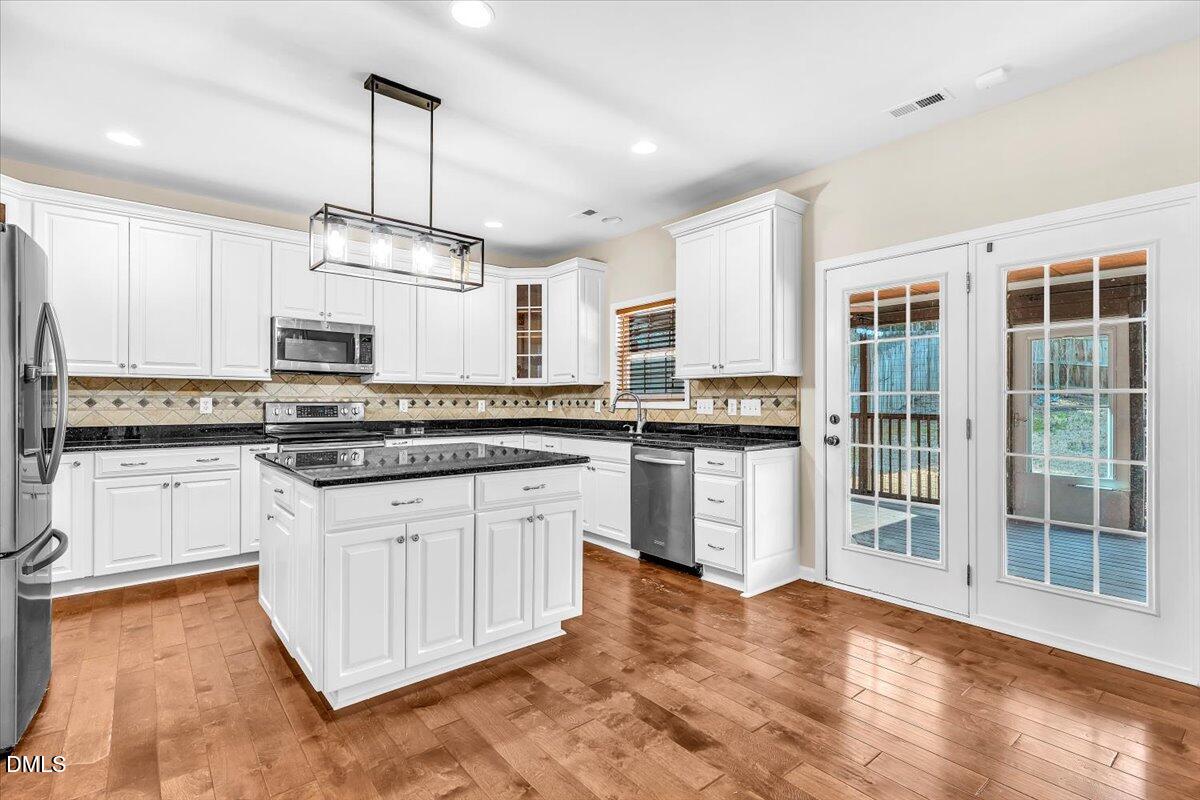 708 Straywhite Avenue Apex, NC 27539 - Photo 18 of 69 a kitchen with stainless steel appliances granite countertop a stove a sink dishwasher a refrigerator and white cabinets with wooden floor
