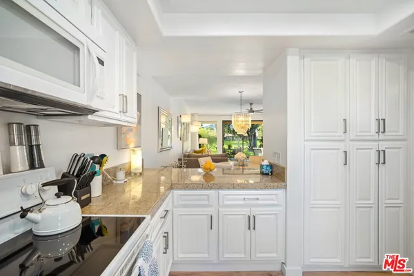 a kitchen with white cabinets and sink