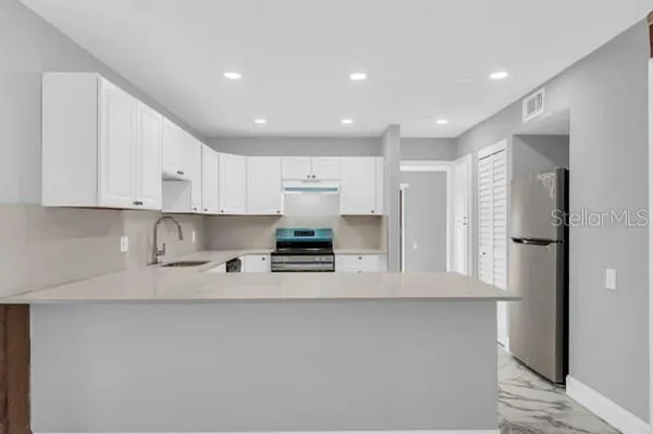a kitchen with stainless steel appliances white cabinets sink and stove
