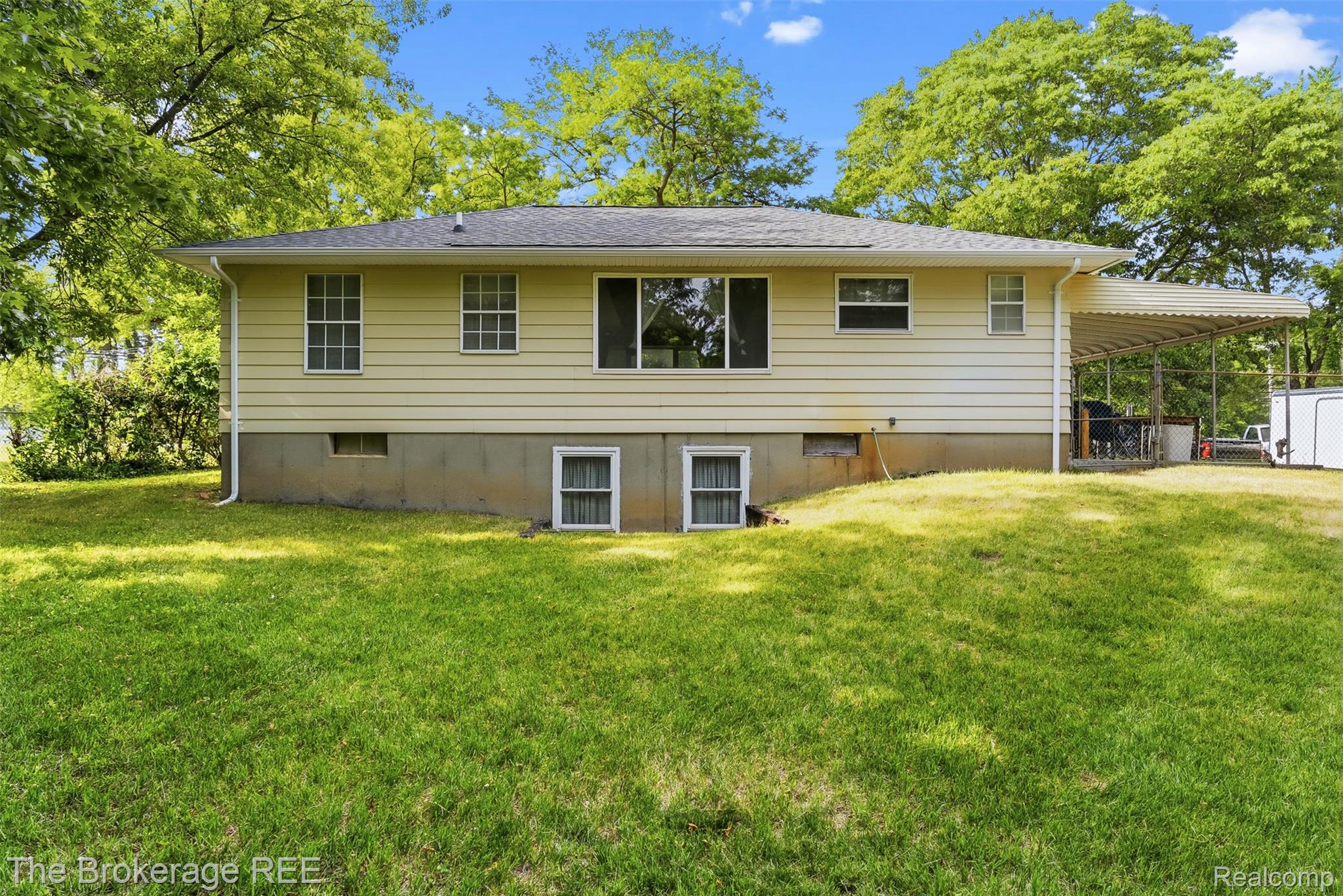 6509 Silver Lake Road Linden, MI 48451 - Photo 42 of 43 Rear exterior featuring light yellow siding, a gray shingle roof, multiple windows, and a covered patio area
