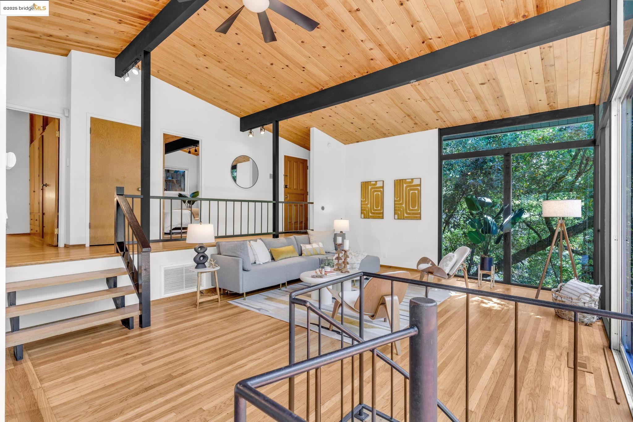 2211 Arrowhead Drive Oakland, CA 94611 - Photo 10 of 52 Living room with light wood-style floors, a wood ceiling with exposed beams, expansive windows, stairs, and a ceiling fan