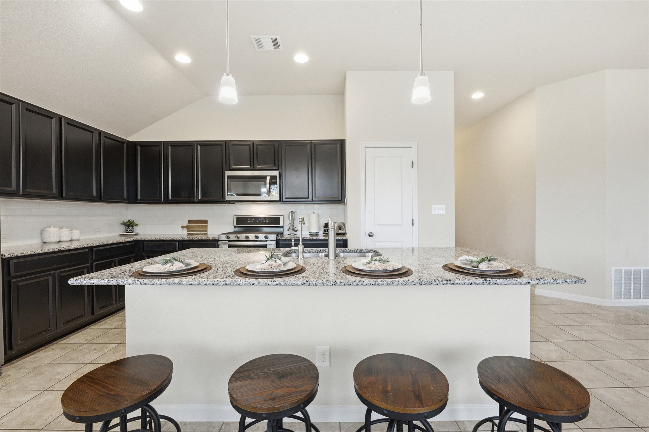 276 Gunnison Way Kyle, TX 78640 - Photo 5 of 28 a kitchen with sink a stove and chairs with wooden floor