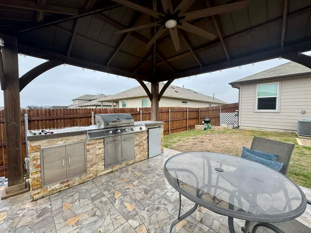 a view of a patio with table and chairs under an umbrella with a small yard