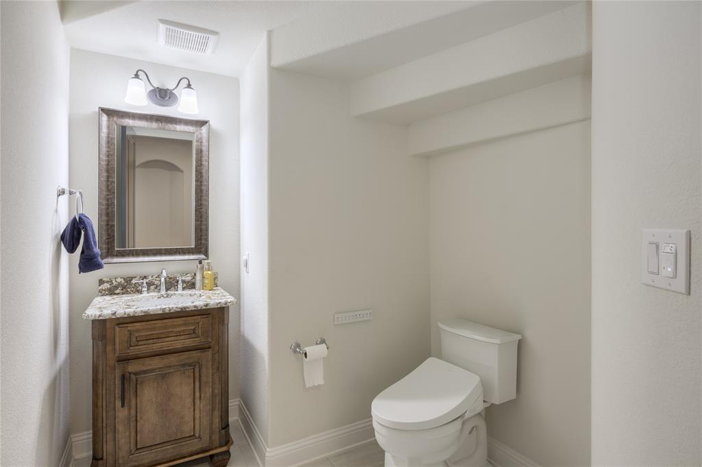 918 Sydney Lane Allen, TX 75013 - Photo 19 of 40 This Powder bathroom features a dark wood vanity with a granite countertop, a framed mirror, and an overhead light fixture