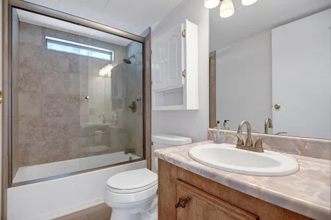 a bathroom with a granite countertop sink a toilet and shower